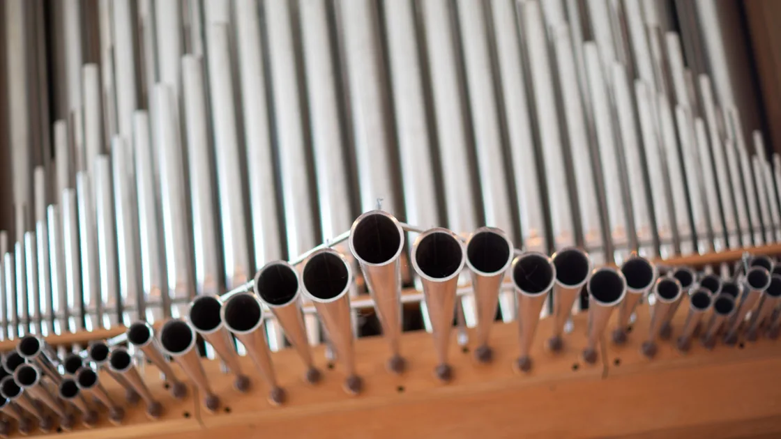 Primer plano de tubos labiales de metal de un órgano alineados por longitud